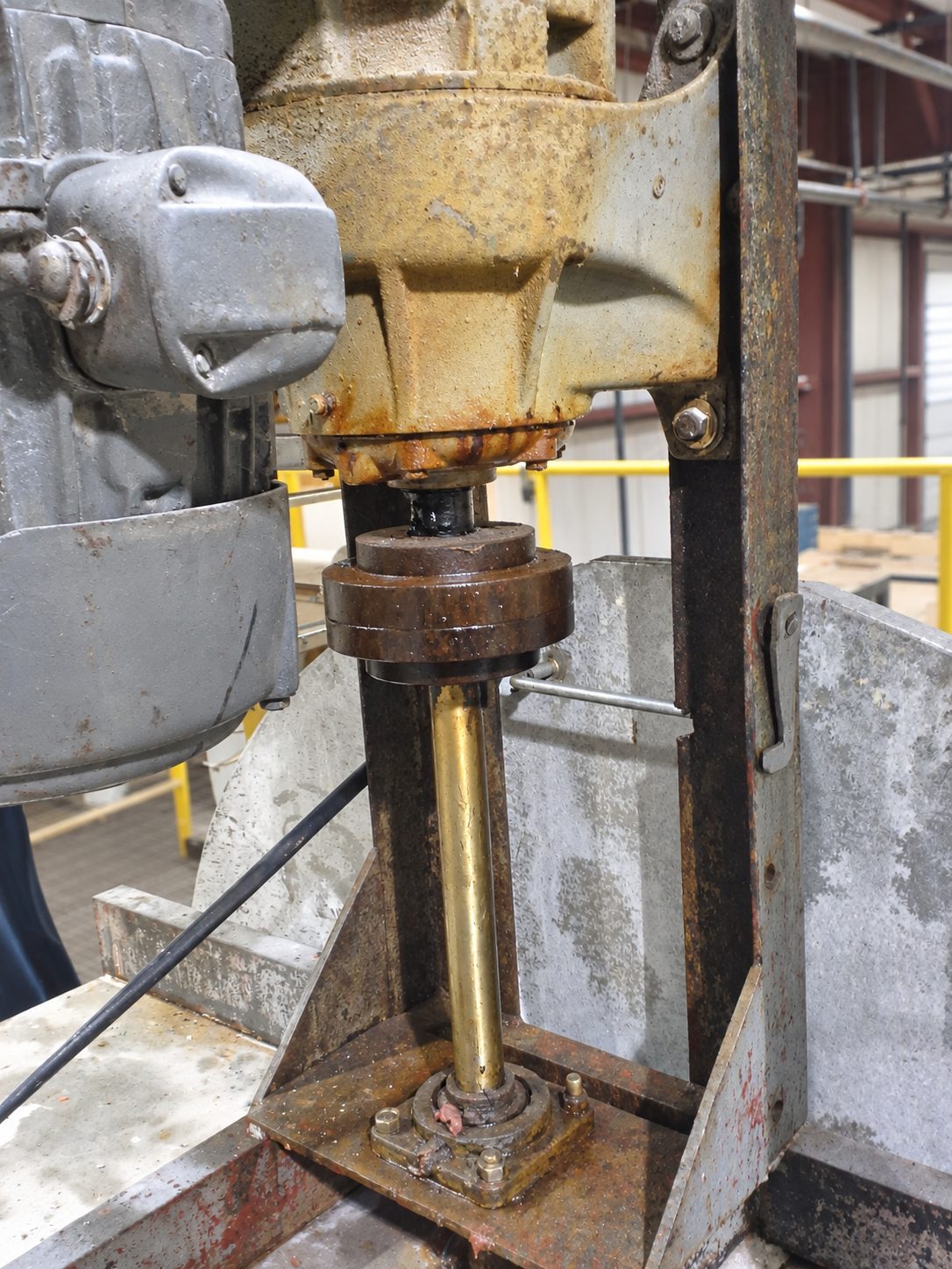 Existing top entry mixer in service, showing a motor and gear reducer on a fabricated frame, the output coupling below, and the shaft passing through a packing gland at the tank top, heavily corroded.